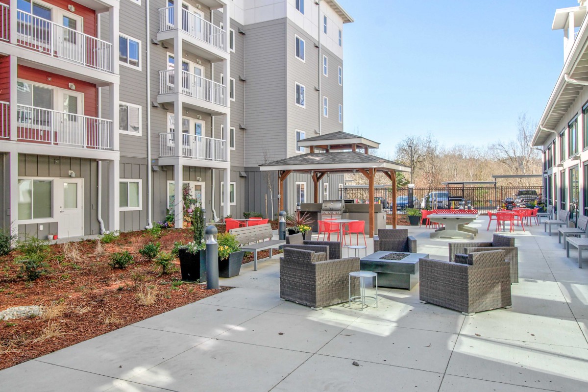 Modern apartment complex with a furnished outdoor patio and gazebo.