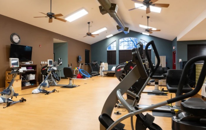 A spacious gym with various exercise equipment and ample natural lighting.