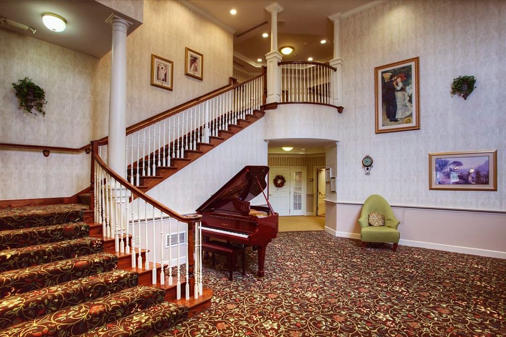 A grand staircase with a wooden banister, accompanied by a classic piano and elegant decor.