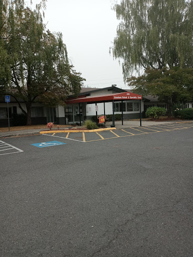 A view of a commercial building with a parking lot and trees in the vicinity.