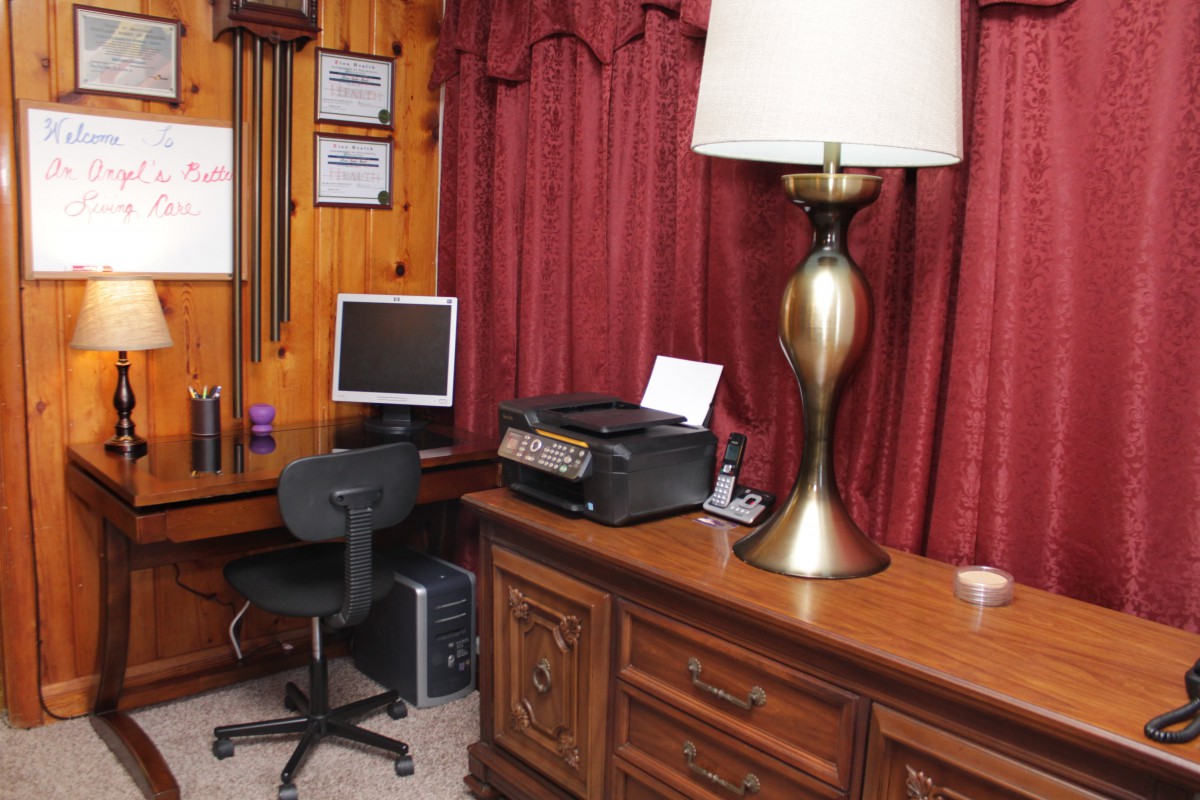 A cozy home office setup with a computer, desk, printer, and lamp.
