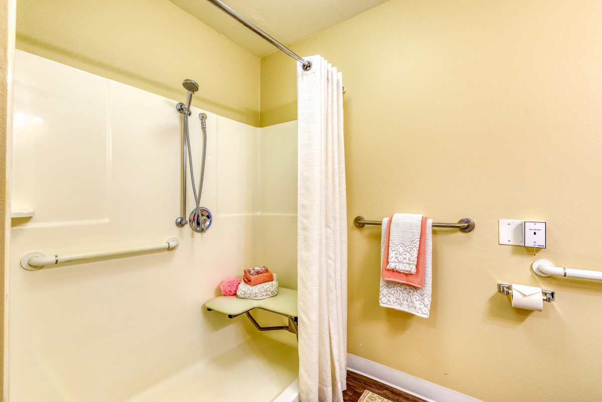 A modern bathroom featuring a shower with a curtain, towel rack, and bath accessories.