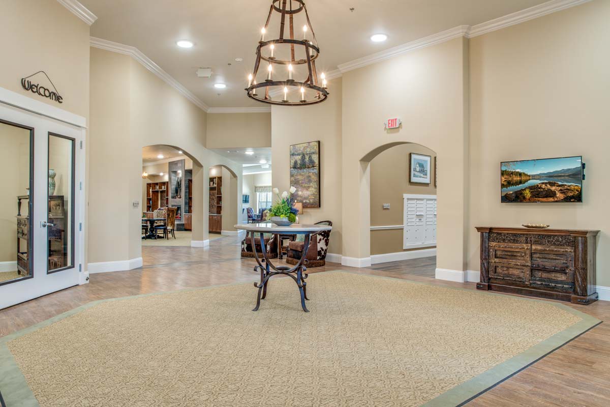 A spacious and elegantly decorated lobby with a central table and a large chandelier.
