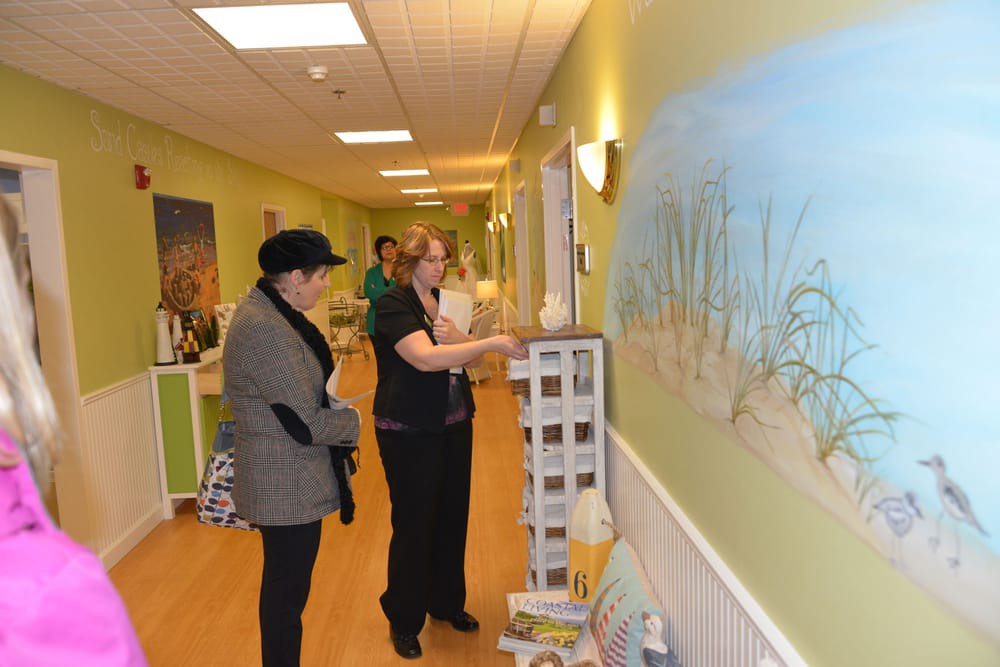 Two people engage in a discussion while observing artwork in a hallway.