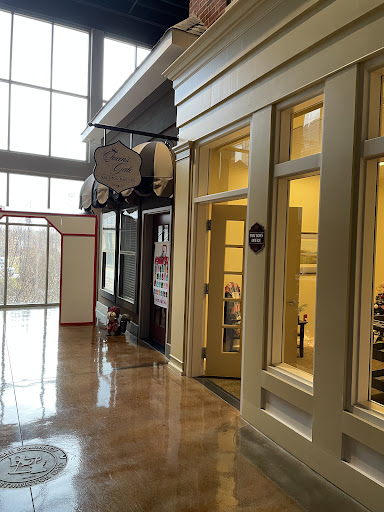 A view of a shopping area featuring modern storefronts and large windows, allowing natural light to illuminate the space.