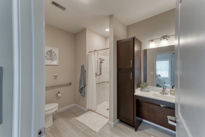 A modern bathroom with a shower, sink, and toilet, featuring contemporary fixtures and storage.