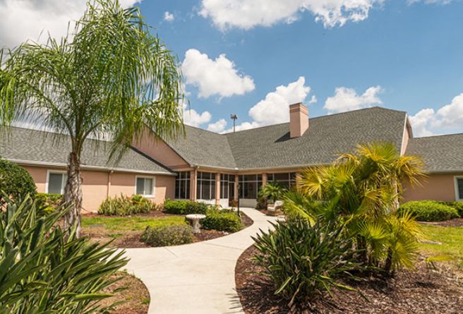 A charming house with a beautifully maintained garden and pathway under a partly cloudy sky.
