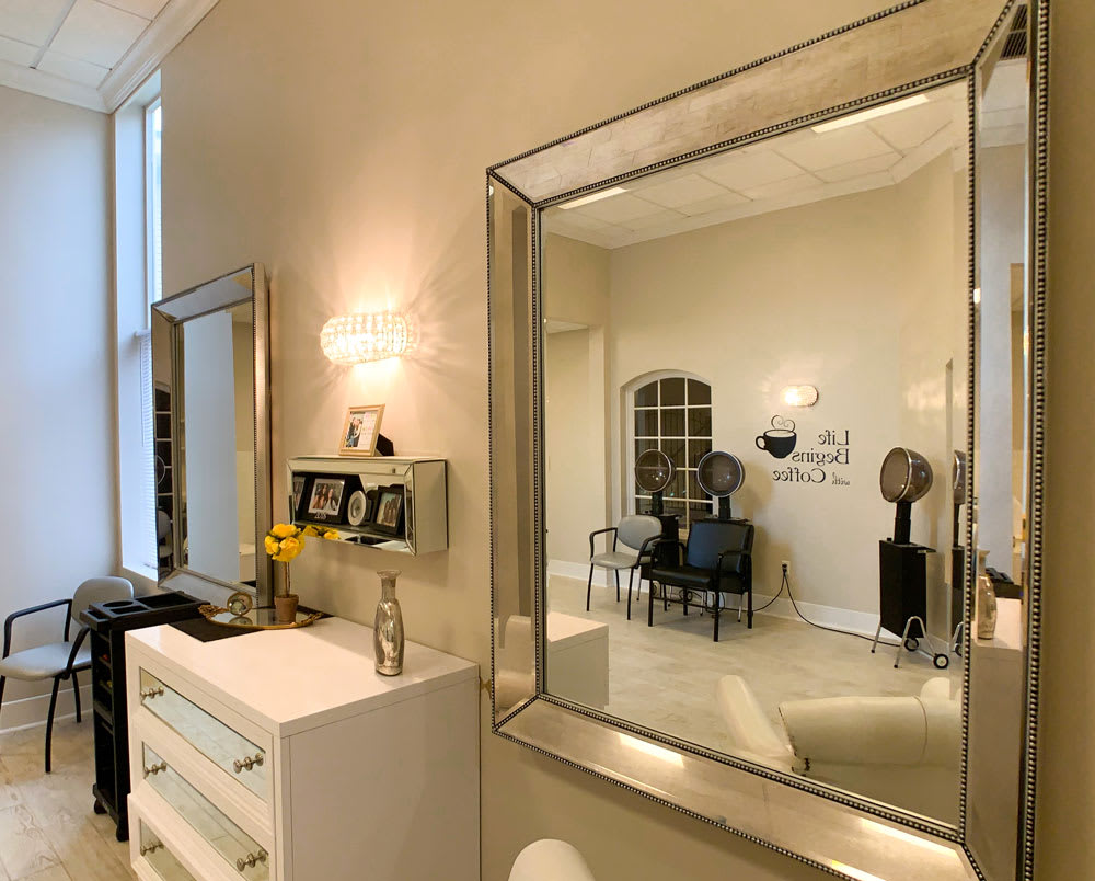 A modern and elegantly decorated living room with a large mirror reflecting the stylish furniture and wall decor.