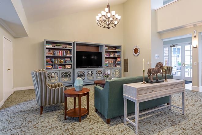 A stylish living room featuring a large bookshelf, a television, comfortable seating, and elegant decor.