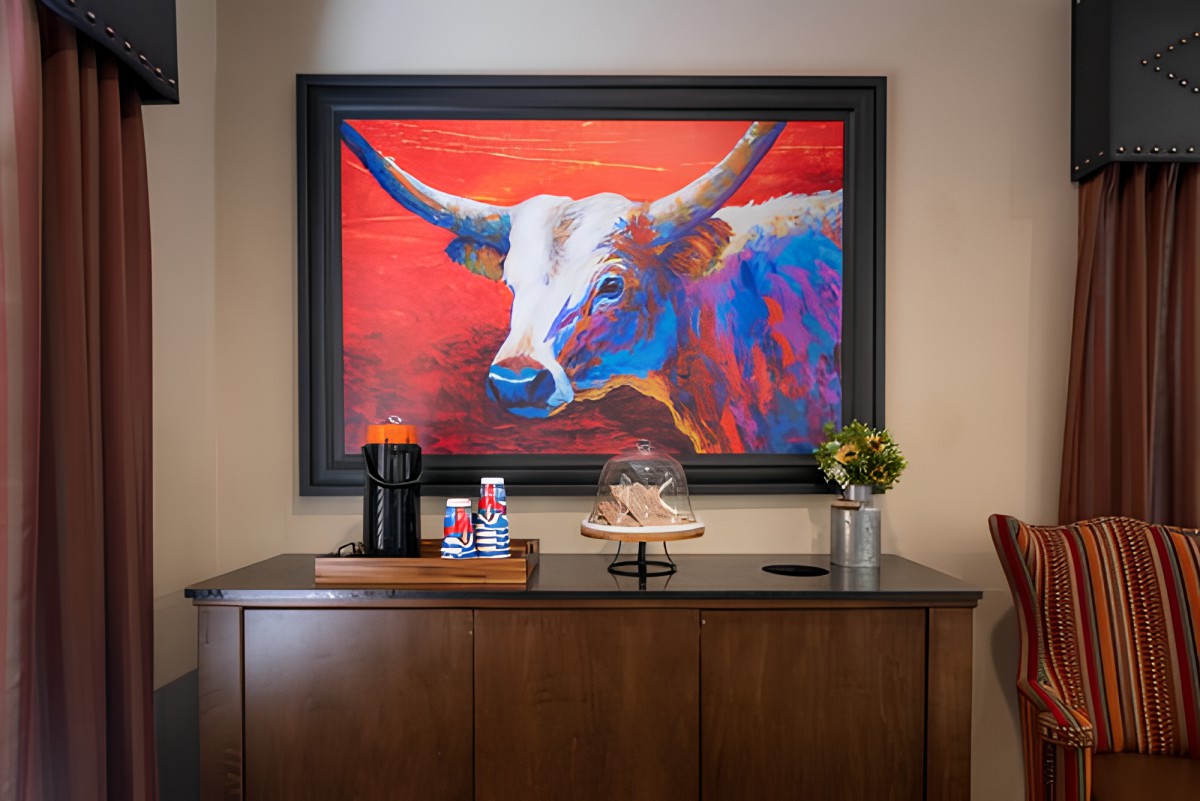 A vibrant bull painting adorns the wall above a cabinet with a coffee station and decorative elements.