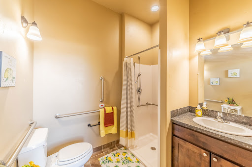 A modern bathroom featuring a shower, toilet, and sink with warm yellow walls.