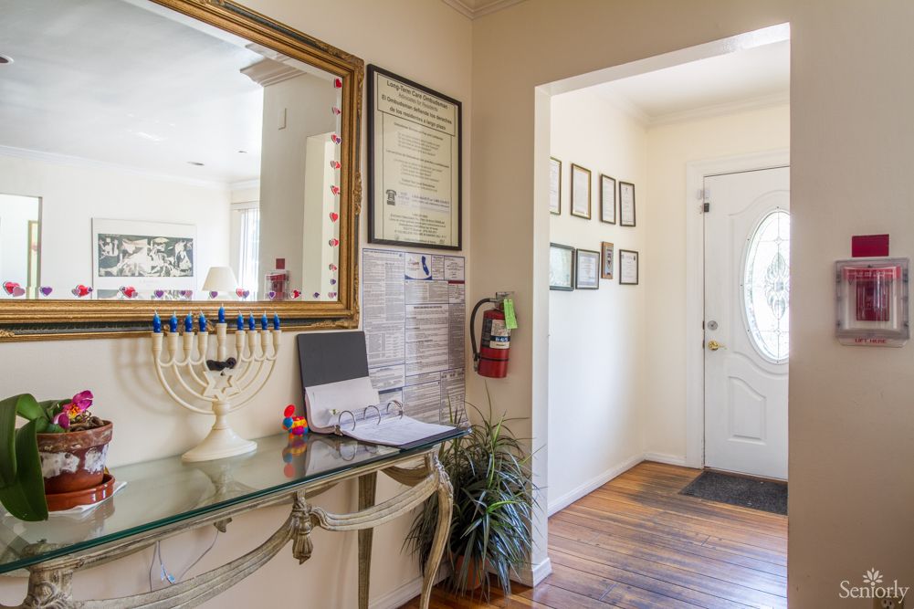 A decorated hallway with a mirror, menorah, and certificates on the wall.
