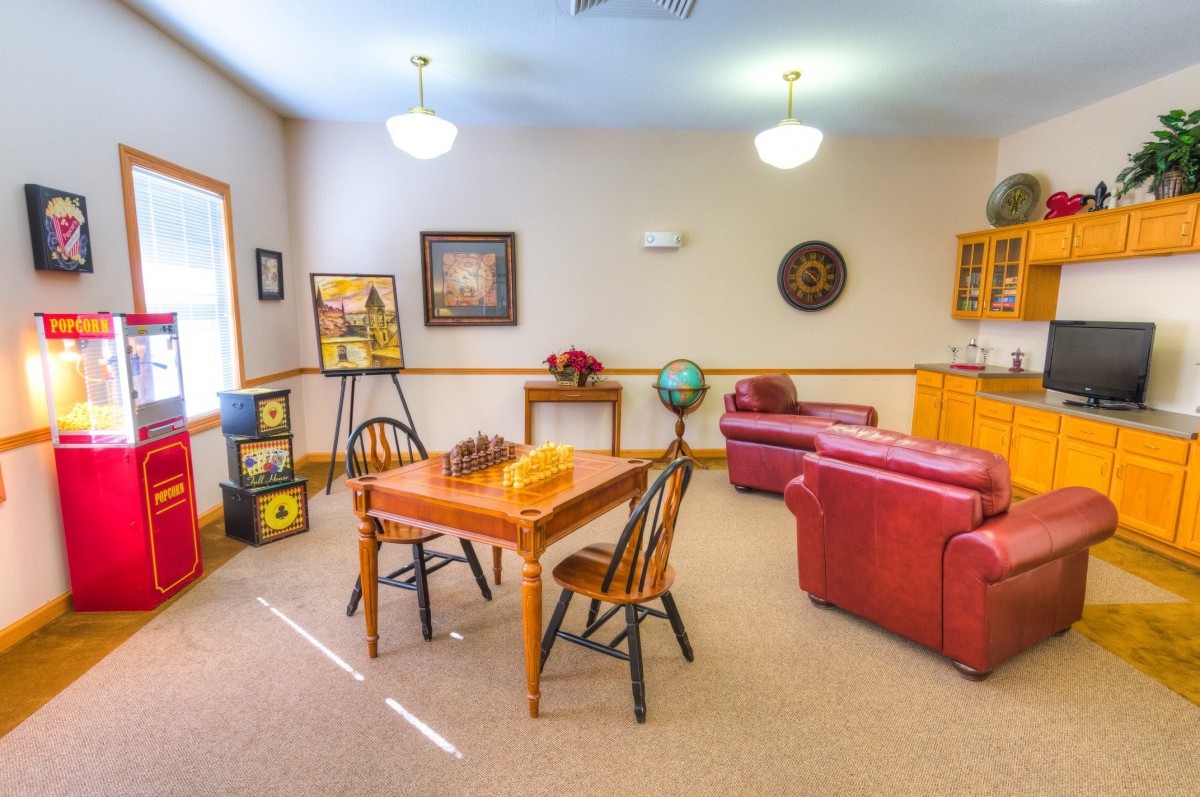 A cozy living room with a table and chairs, a red couch, artwork on the walls, and a globe for decoration.