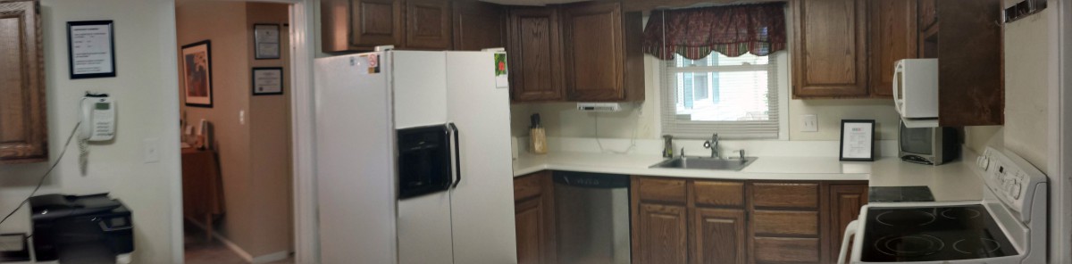 A kitchen with wooden cabinets, a white refrigerator, and a dishwasher.
