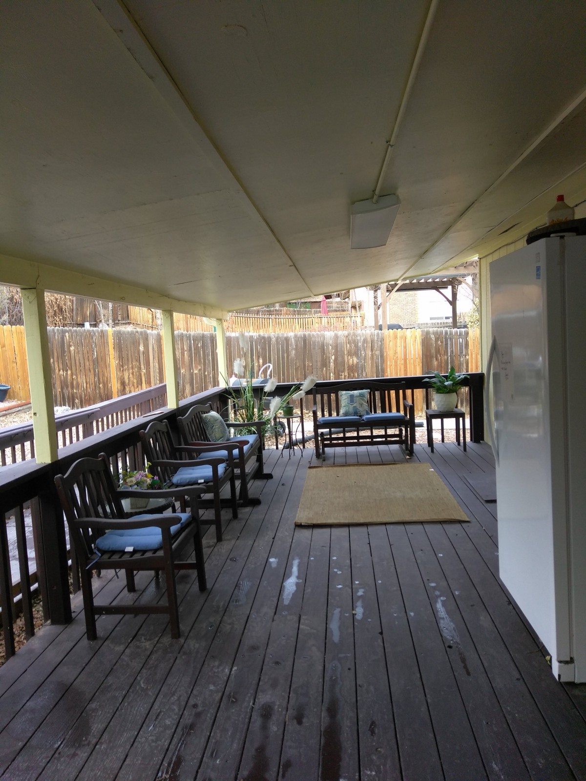 A cozy covered porch with wooden flooring and outdoor seating.