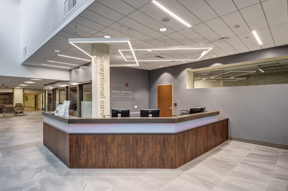 A modern office lobby featuring a sleek reception desk with minimalist design elements and contemporary lighting.