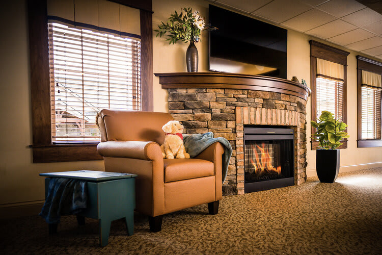 A cozy living room featuring a stone fireplace and a leather armchair.