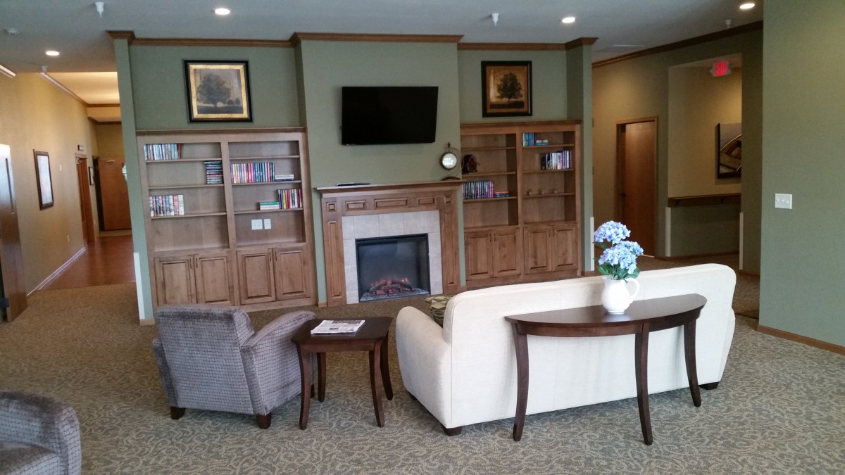 A cozy living room featuring sofas, a fireplace, and built-in bookshelves.