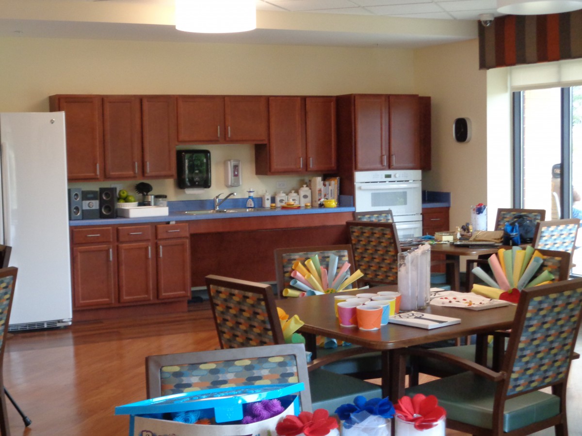 A cozy kitchen and dining area with wooden cabinets, tables, and chairs.