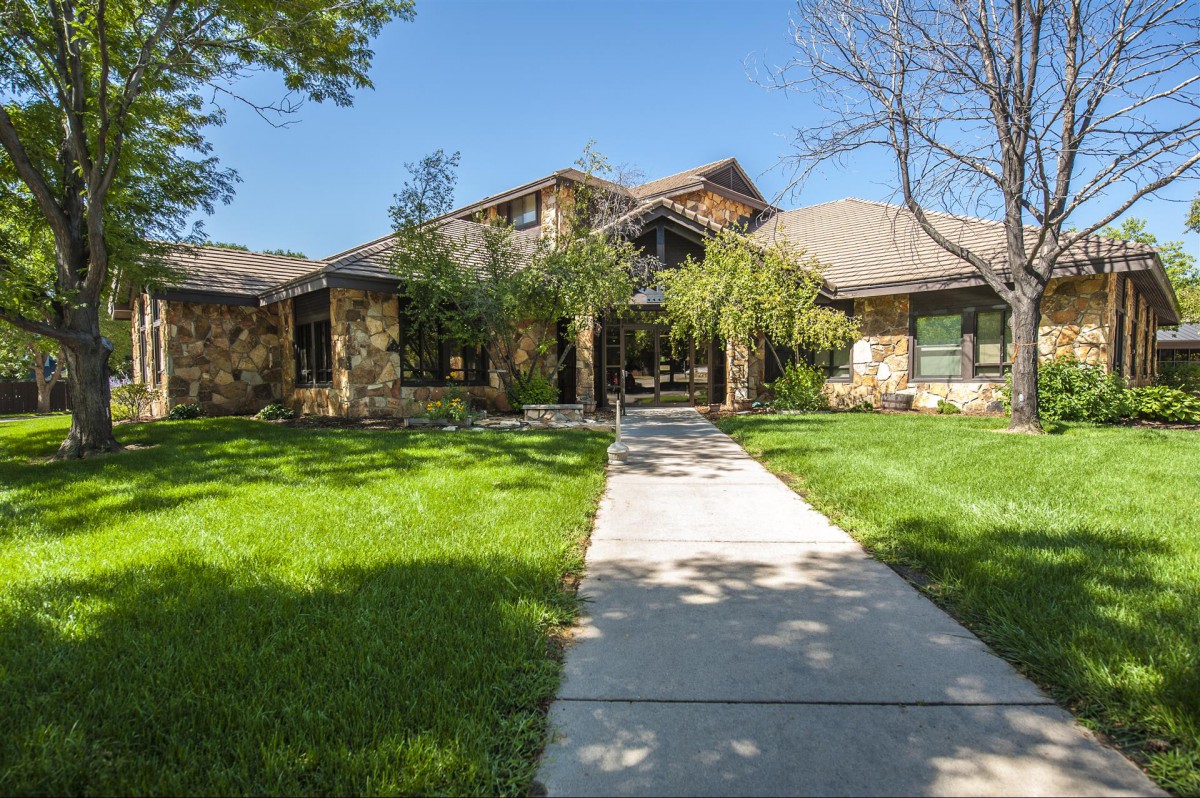 A beautiful residential house with a well-maintained lawn and trees under a clear blue sky.