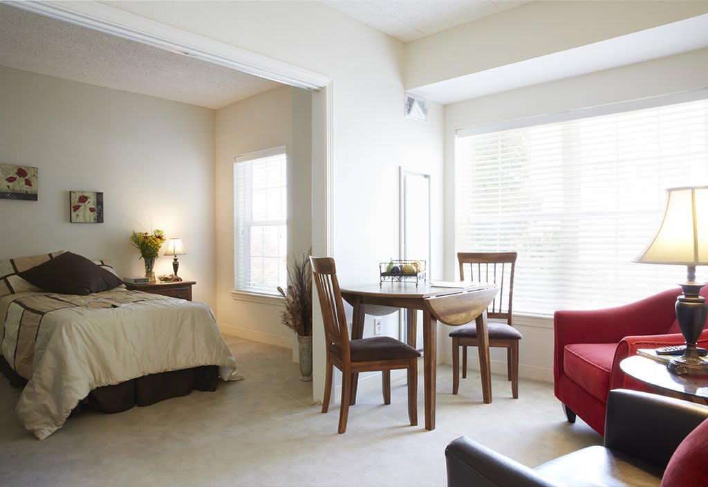 A cozy apartment interior featuring a bedroom, dining area, and living space.