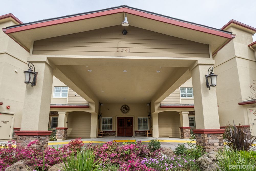 A well-maintained building entrance with a covered porch and vibrant flower landscaping.