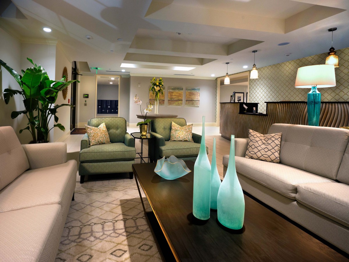 A modern living room with stylish decor featuring green and beige furniture, decorative vases on the coffee table, and elegant lighting.
