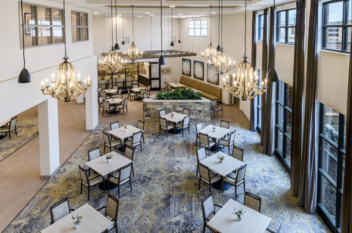 A beautifully designed restaurant interior featuring chandeliers and neatly arranged tables and chairs.