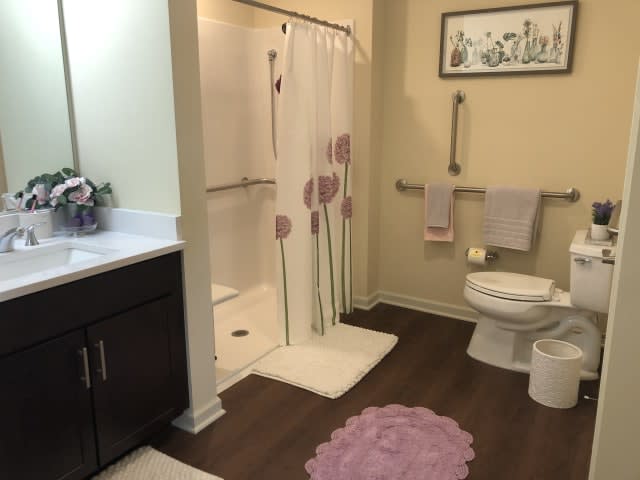 A neatly organized bathroom featuring a shower with a floral curtain, a toilet, and a vanity.