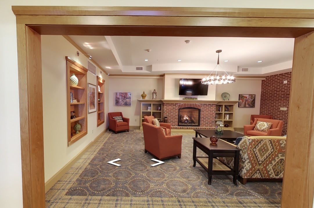 A cozy living room with a fireplace, comfortable seating, and bookshelves.