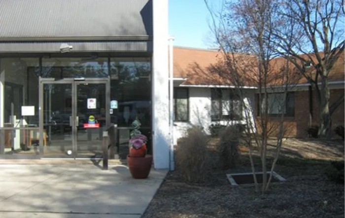 Entrance of a building with plants and trees surrounding it.
