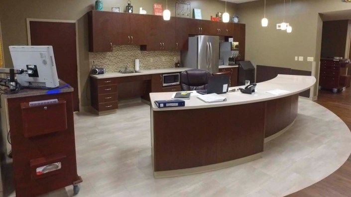 A modern office reception area with a curved desk and cabinetry.