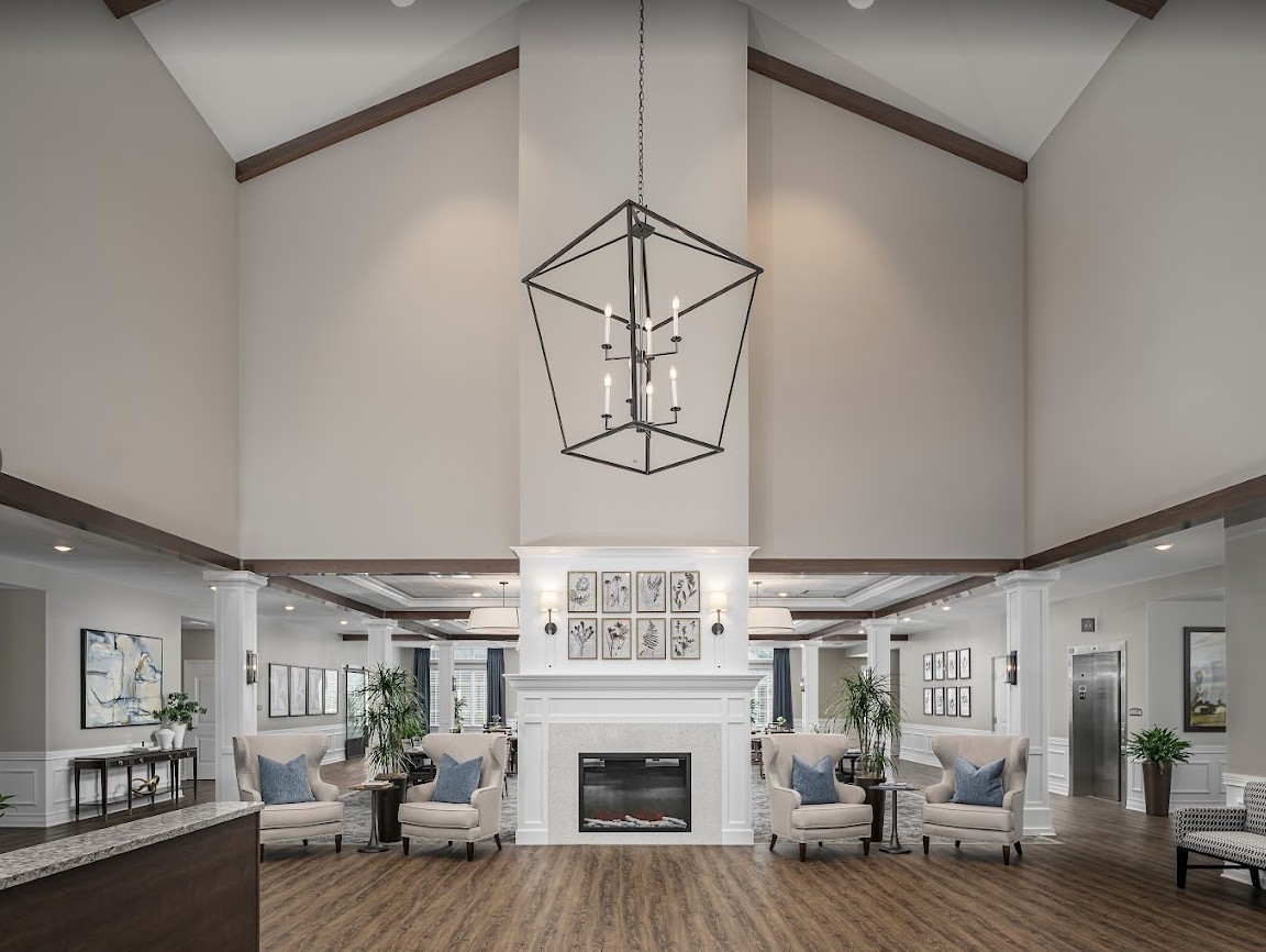 A modern living room with high ceilings, featuring a central fireplace and stylish chandelier.