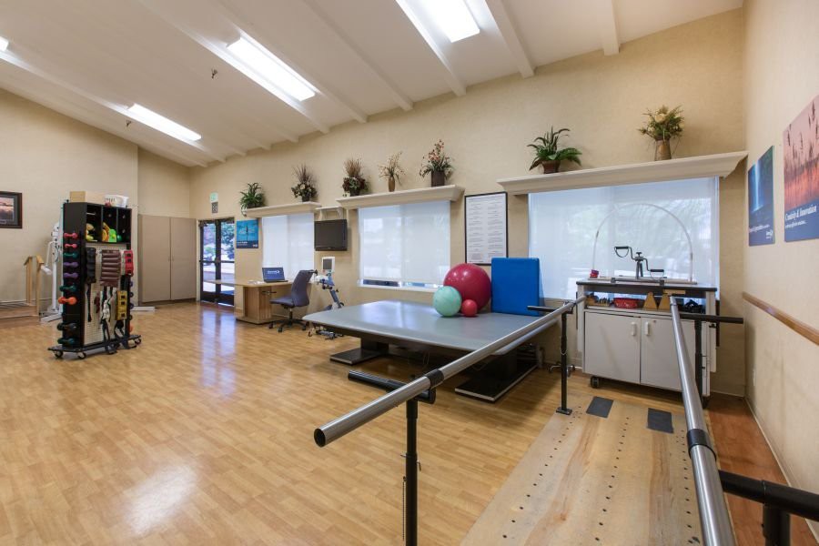 A rehabilitation therapy room equipped with exercise equipment and safety bars.