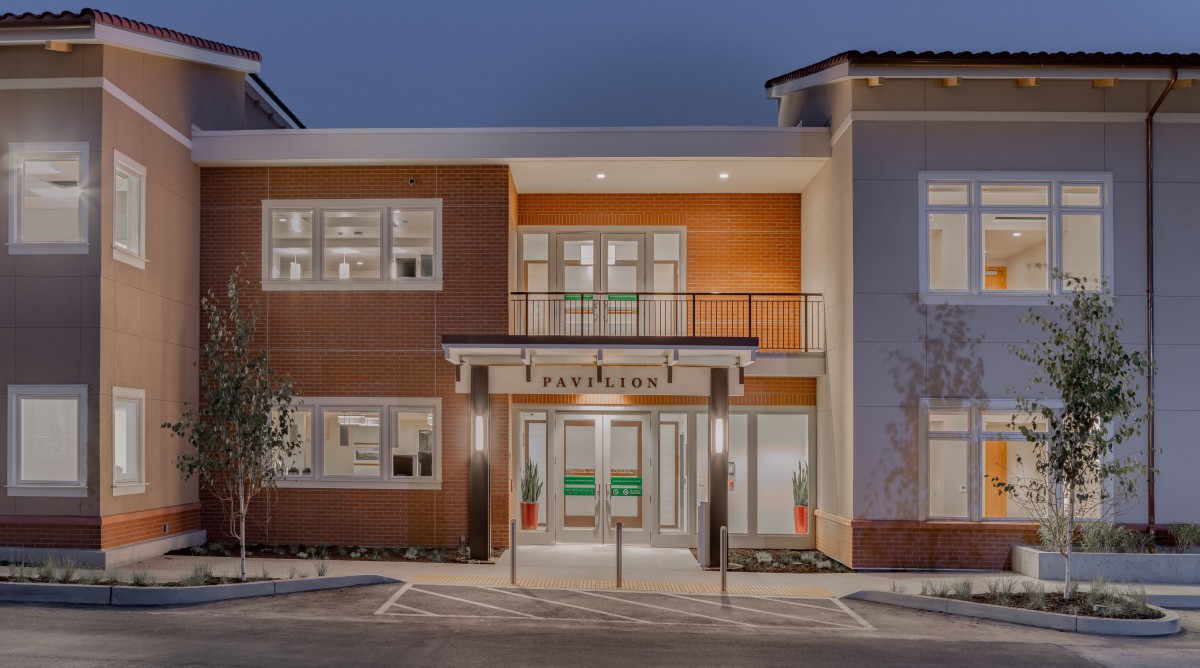A modern building facade illuminated at night with a prominent entrance.