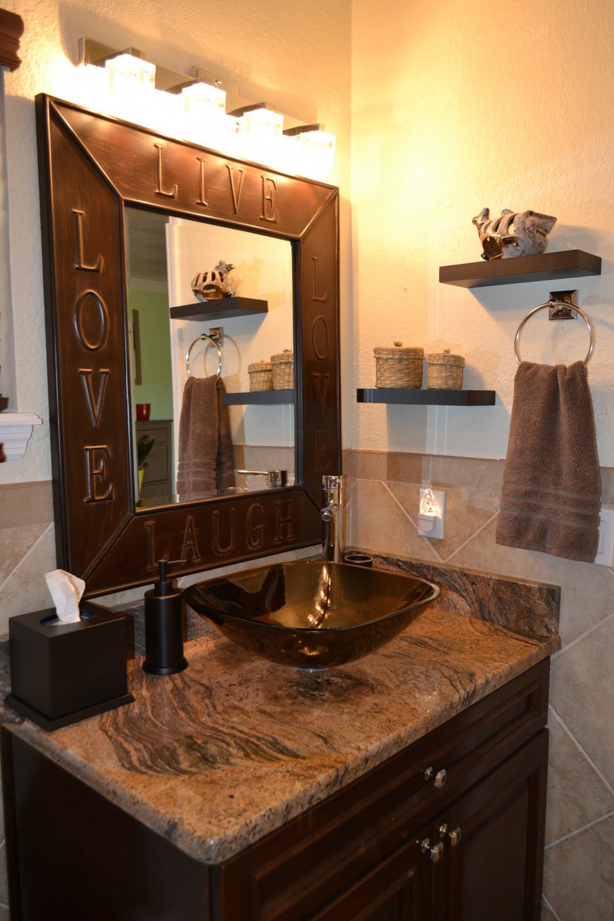 A stylish bathroom with a decorative mirror, countertop sink, and neatly arranged shelves.