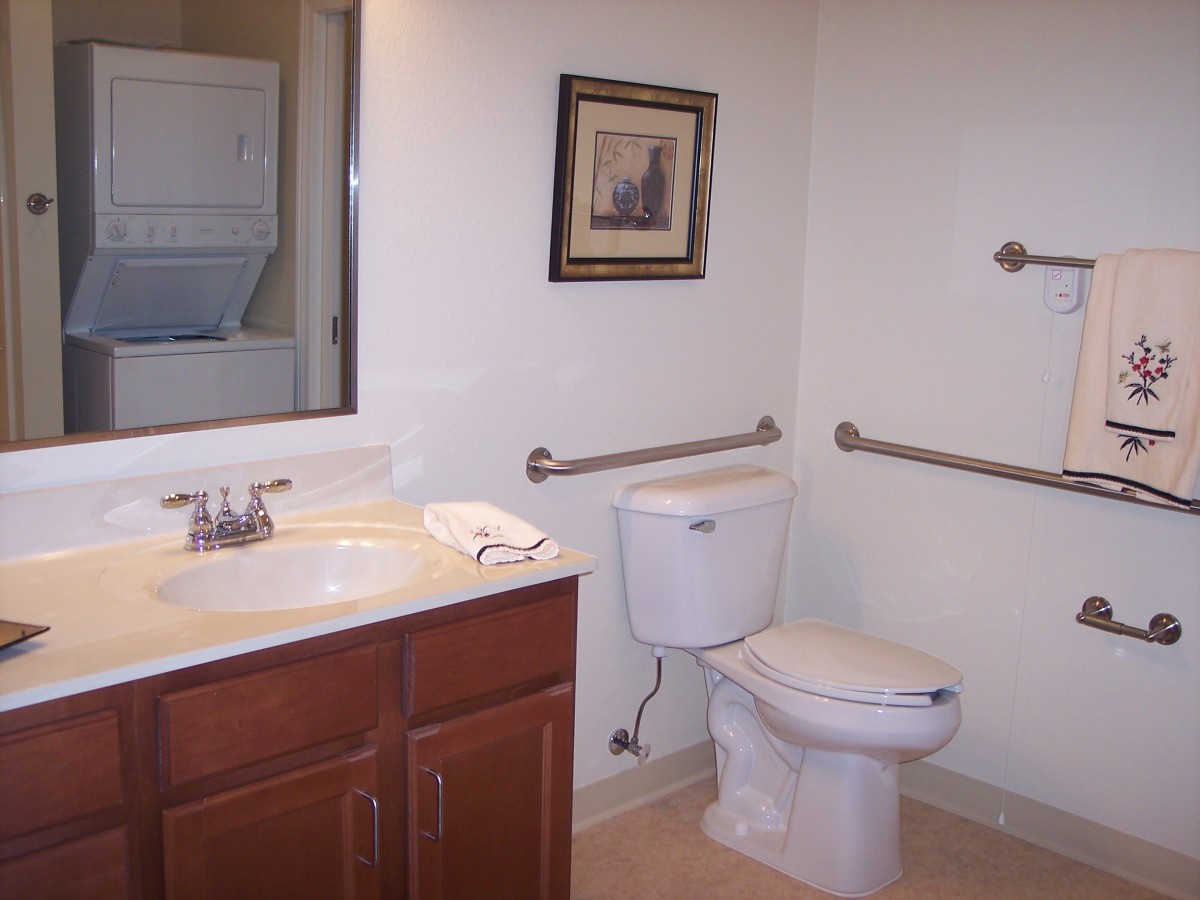 A clean bathroom with a toilet, sink, and stacked washer dryer unit.