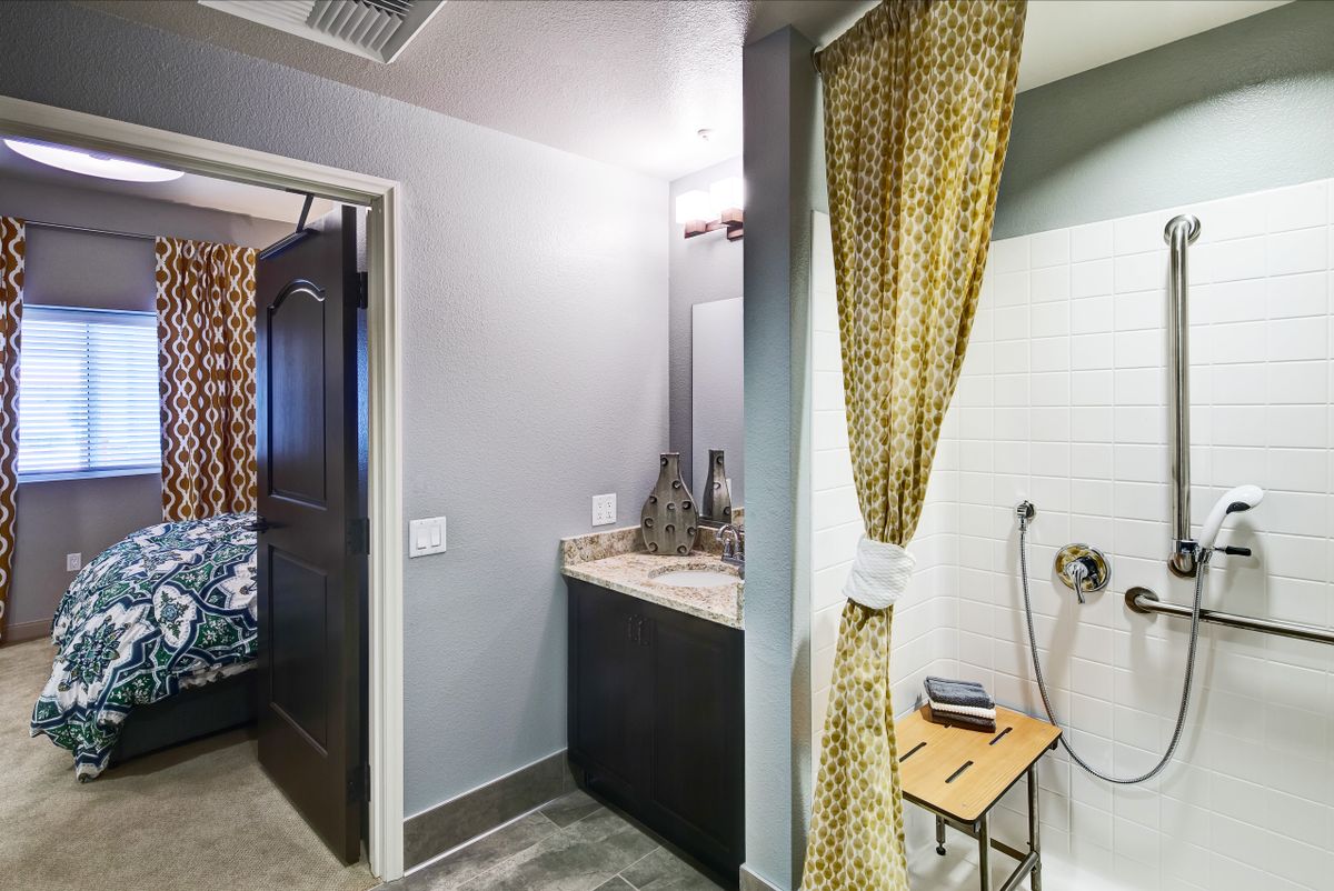A modern bathroom featuring a sink, mirror, and shower with a patterned curtain.
