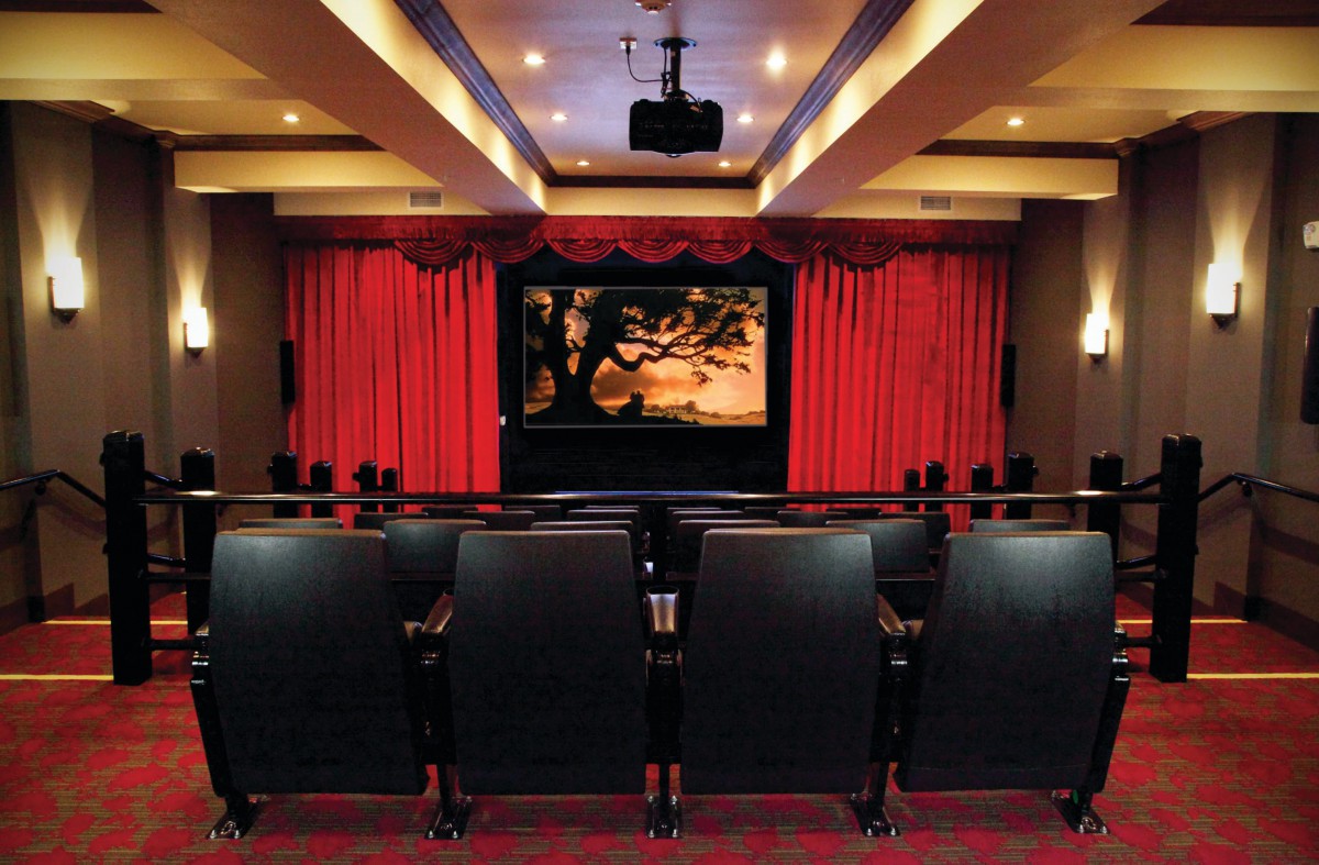 A cozy movie theater with red curtains and rows of seats facing a screen.