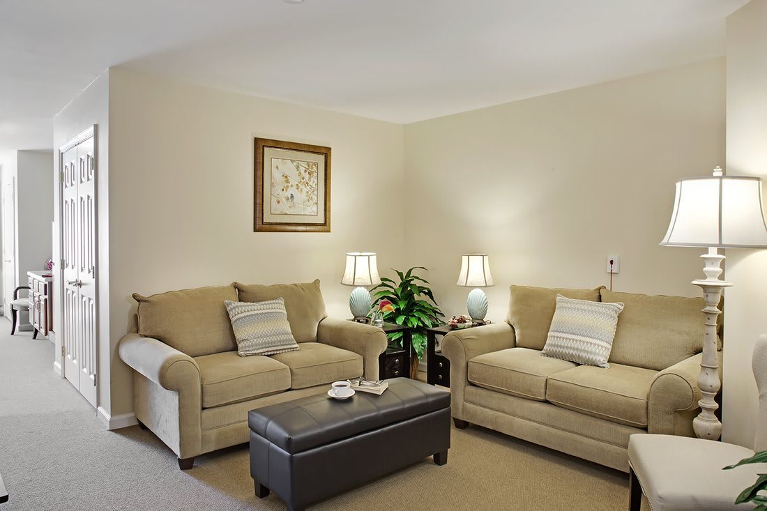 A cozy living room with beige sofas, a dark coffee table, and ambient lighting from side lamps.
