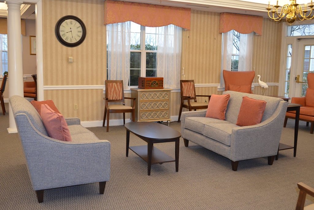 A cozy living room with two sofas, a coffee table, and chairs set against a striped wallpaper backdrop.