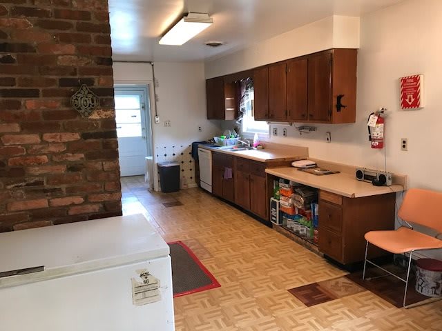 A cozy kitchen with wooden cabinets and a brick feature wall.
