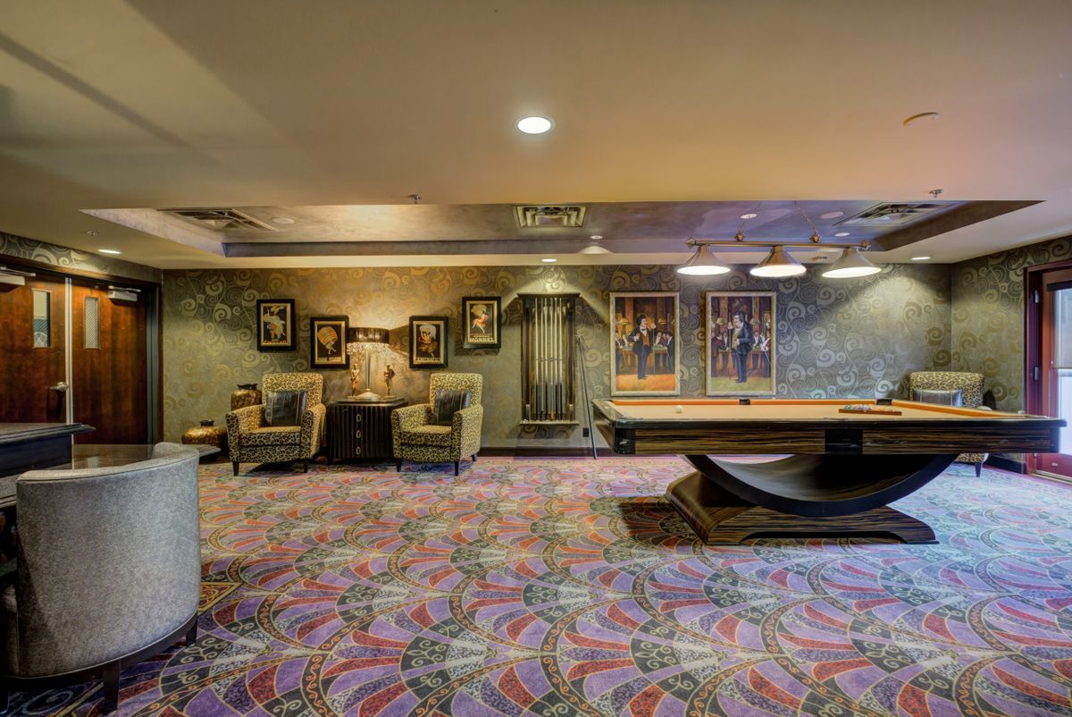 A cozy recreation room with seating and a pool table, decorated with artwork and soft lighting.