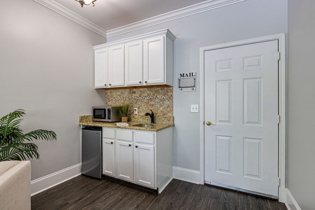 A small modern kitchen corner with white cabinets, a countertop, and appliances including a mini fridge and microwave.