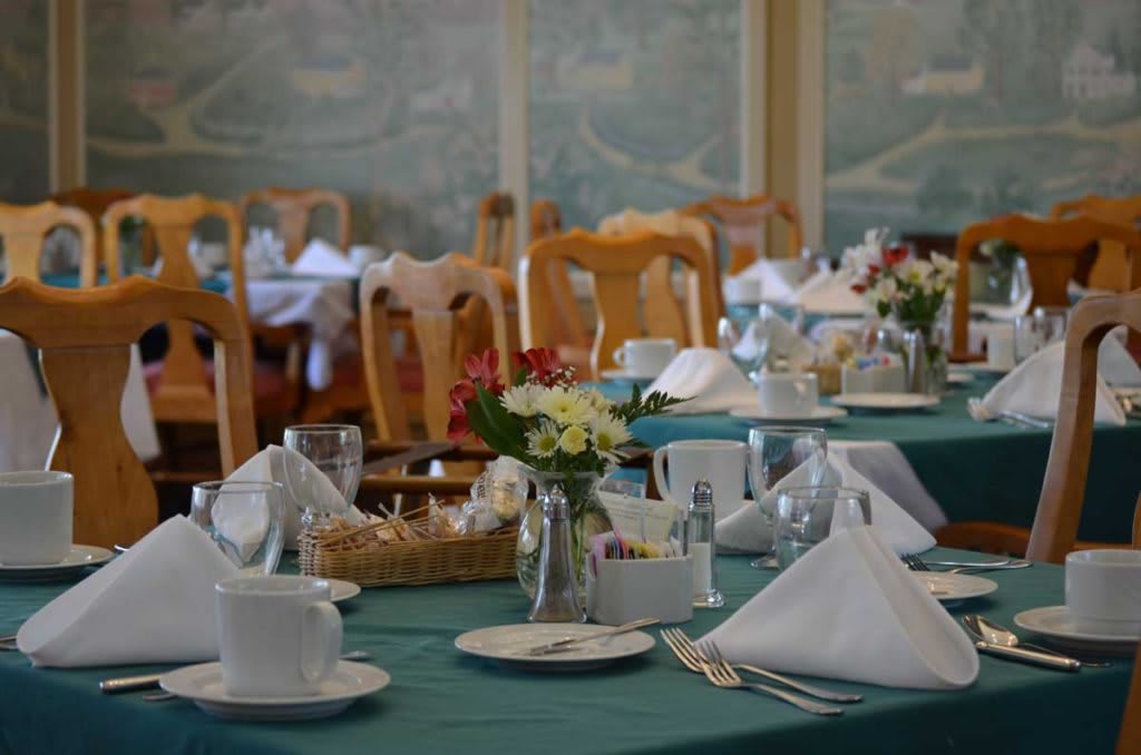 A beautifully set dining table in a restaurant with elegant decor and fresh flowers.