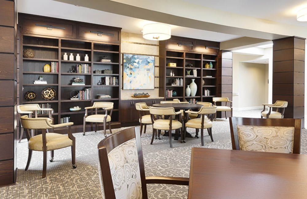 A modern library space with bookshelves, tables, and chairs.