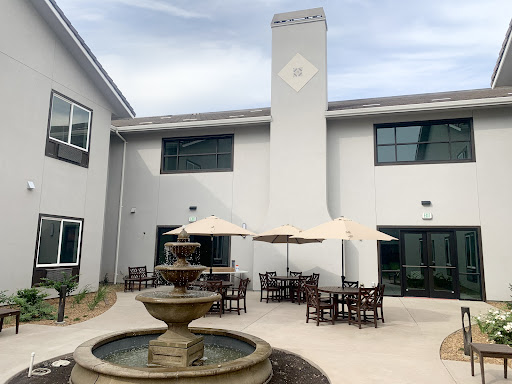 A serene outdoor courtyard featuring a fountain and comfortable seating with umbrellas.