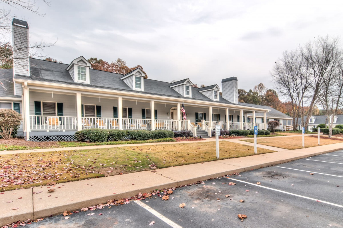 A suburban house with a spacious front porch and adjacent parking lot.