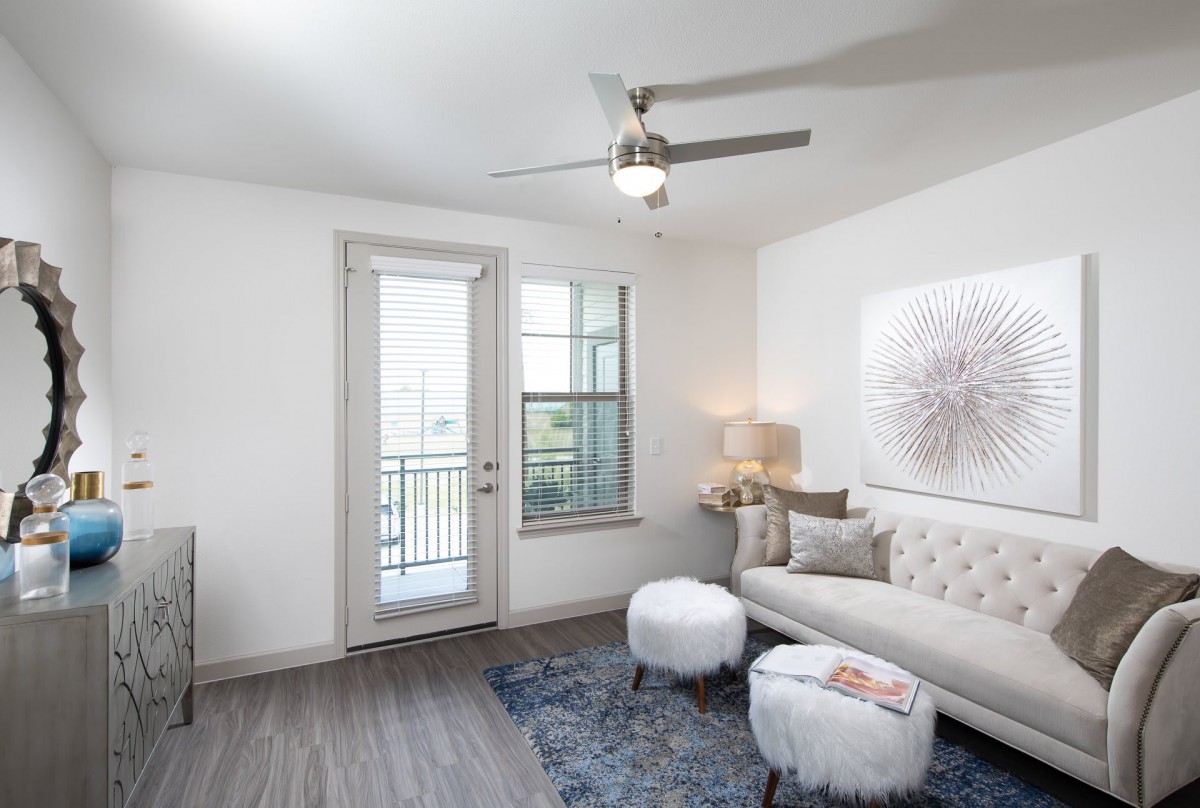 A modern and minimalist living room with a comfortable sofa, stylish artwork, and a ceiling fan.