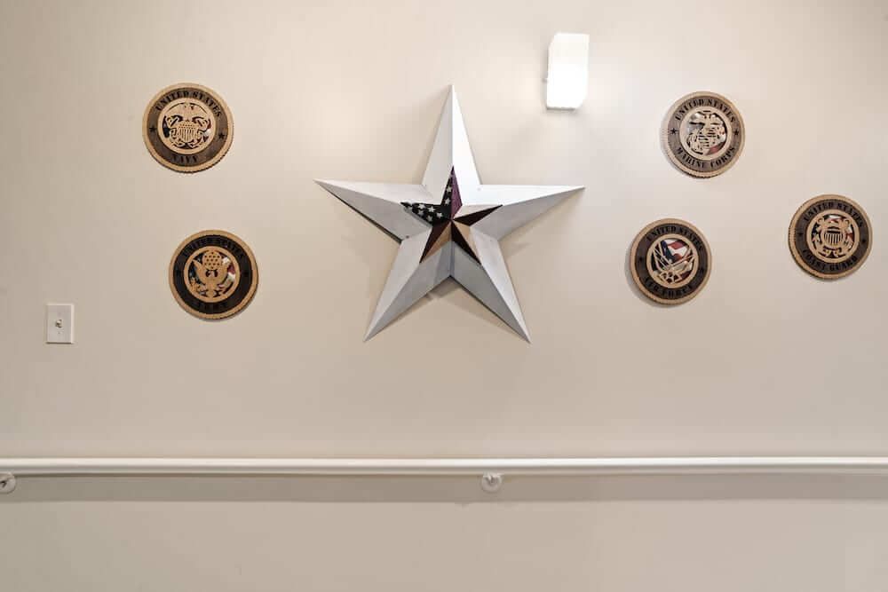 A wall decorated with a large metallic star and four military emblems.